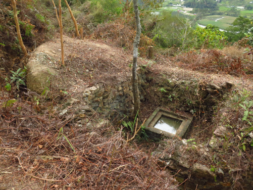 Inside a stone wall revetted enclosure, a 2-metre deep concrete shaft was constructed near a large rectangular pillbox close to the top of the knoll on the western side. Square in plan and with steel rungs for access on its southern side, its purpose has yet to be determined. Possible uses might have been water supply, field sanitation or some sort of shelter. (photo credit: The University of Hong Kong)